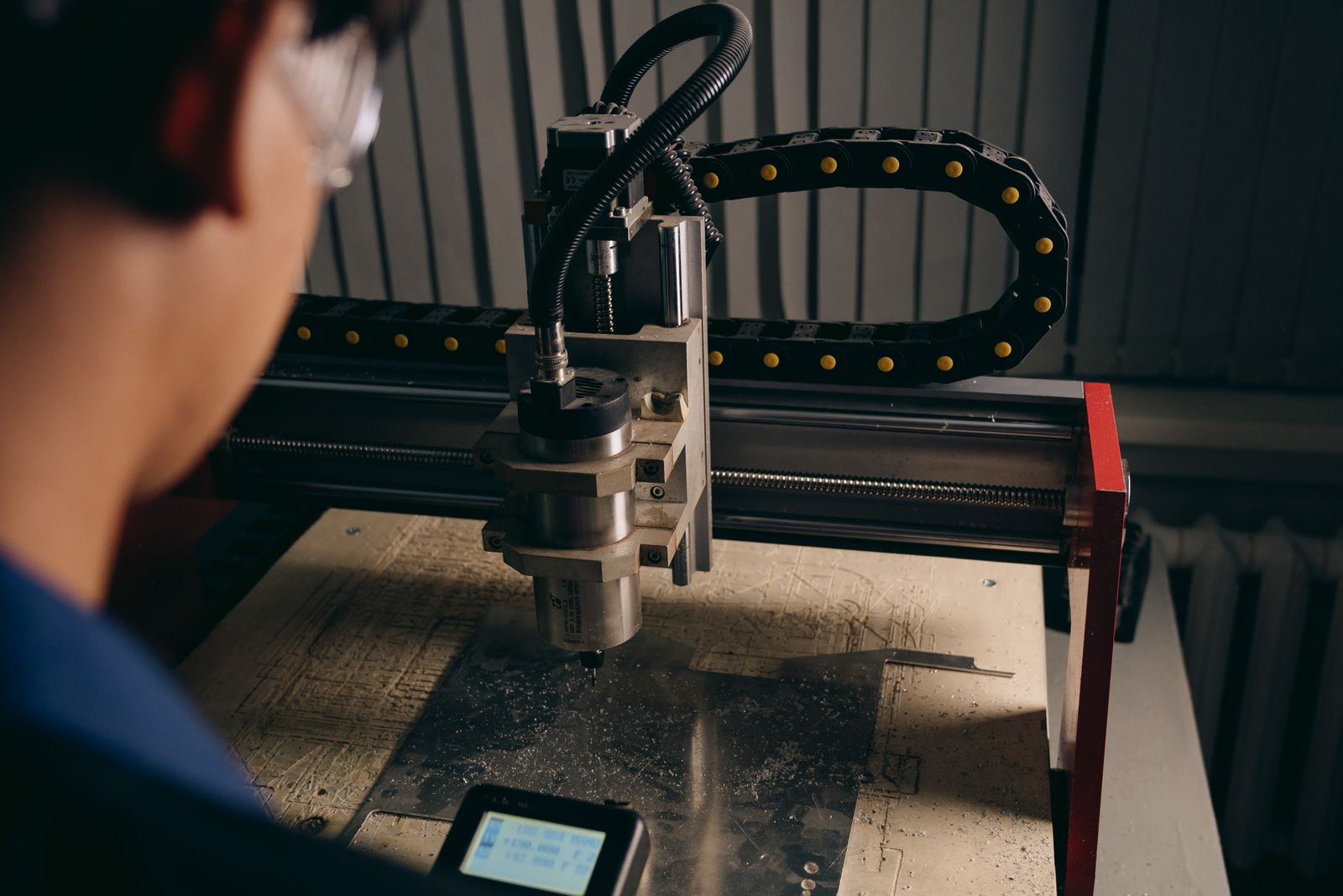Persona junto a una máquina CNC en un taller industrial; fotografía de archivo, no de un cliente de Ulertu